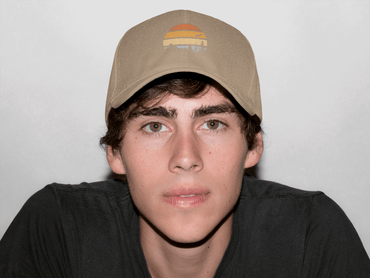 Beige Madeira Vintage Cap featuring a mountain logo, worn by a young man. A versatile and timeless adventure-style cap.
