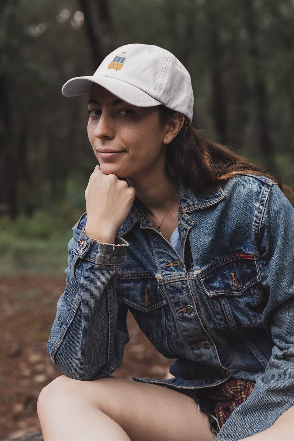 White Lisbon Tram Cap with minimalist embroidery, worn by a woman in a denim jacket. A trendy unisex cap celebrating Lisbon's tram heritage.