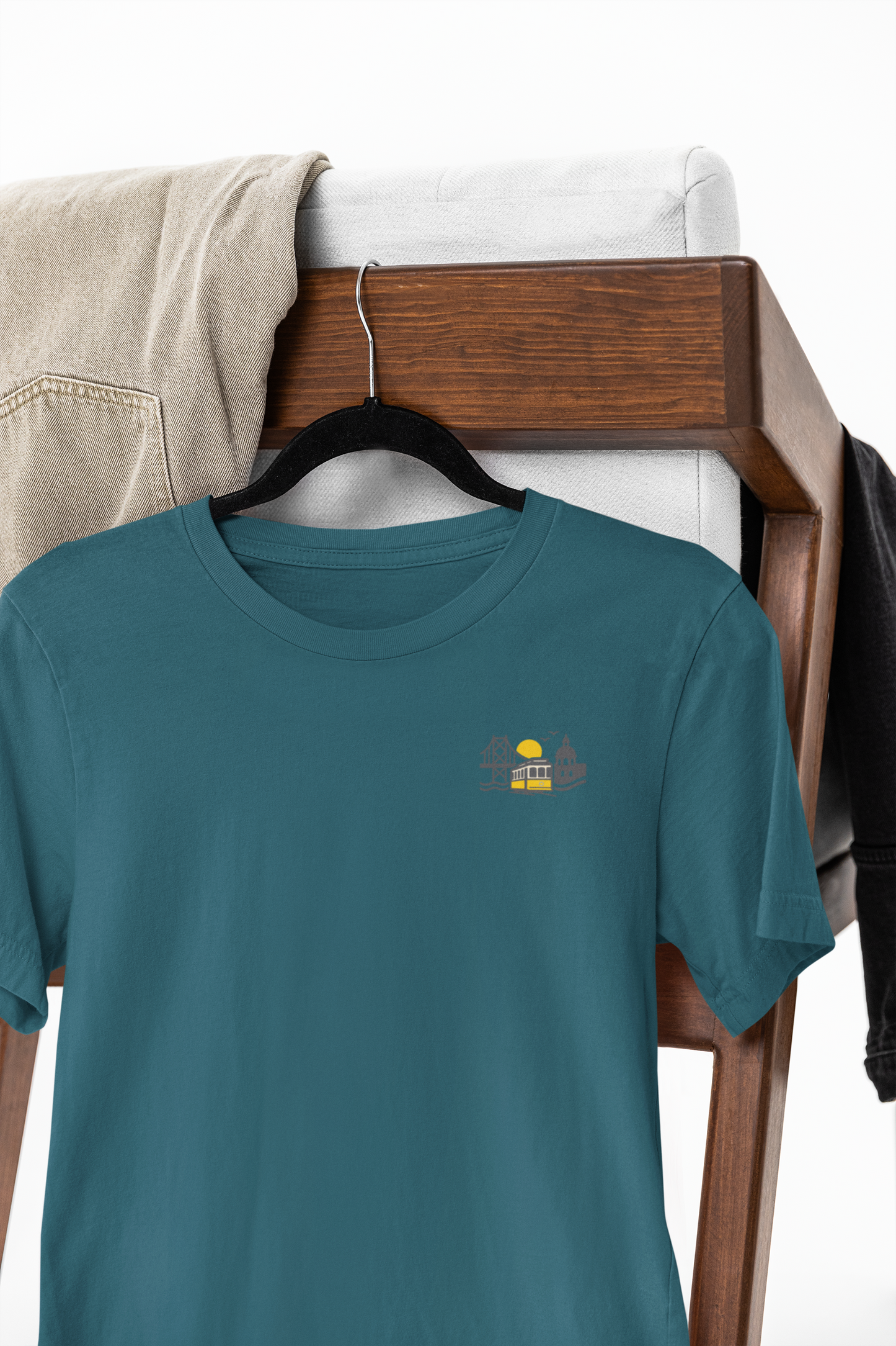 Teal t-shirt with a small yellow graphic on a wooden hanger against a white background