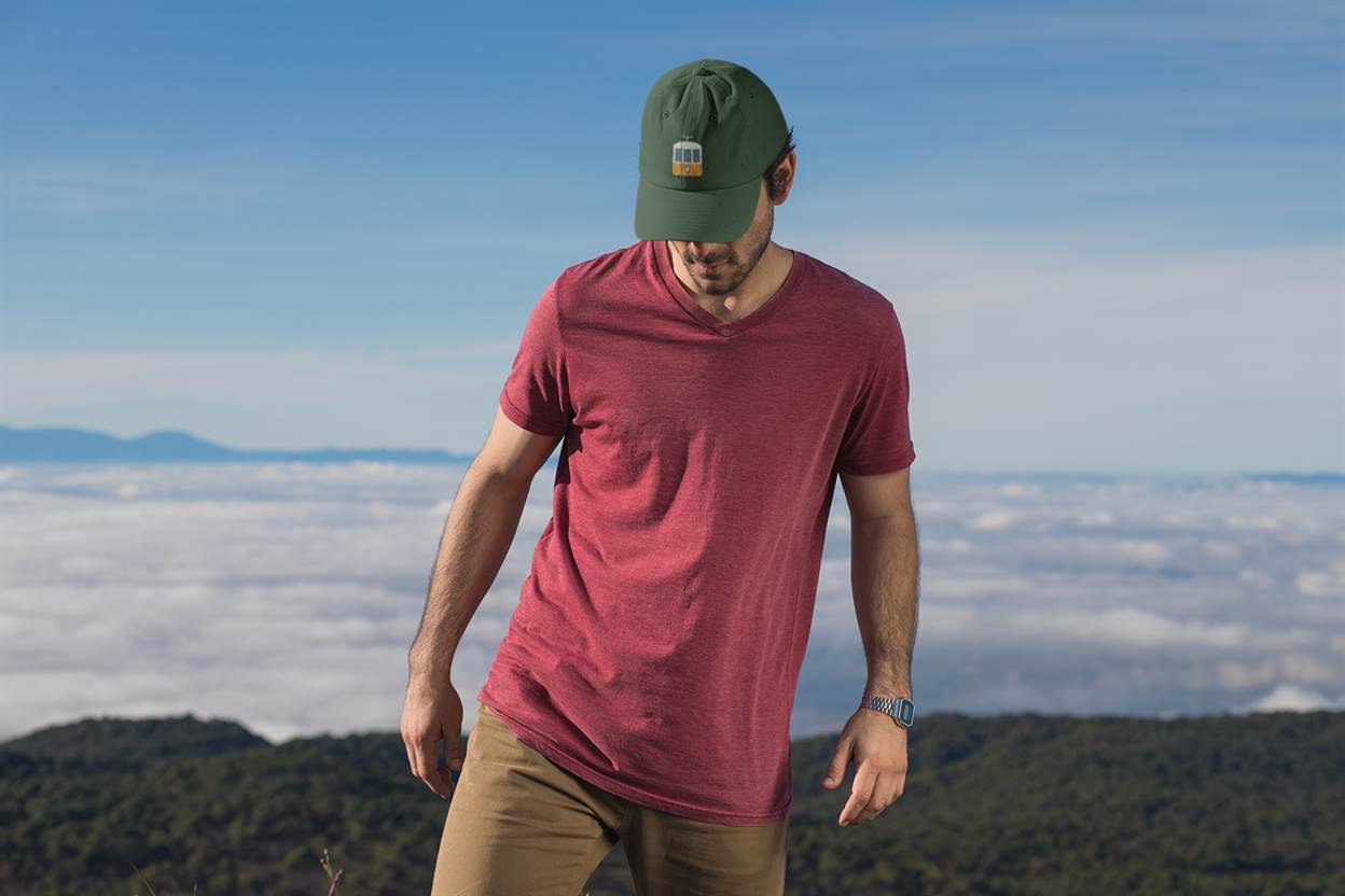 Green Lisbon Tram Cap with minimalist embroidered tram logo, worn by a man hiking above the clouds. A stylish unisex tribute to Lisbon's tram culture.