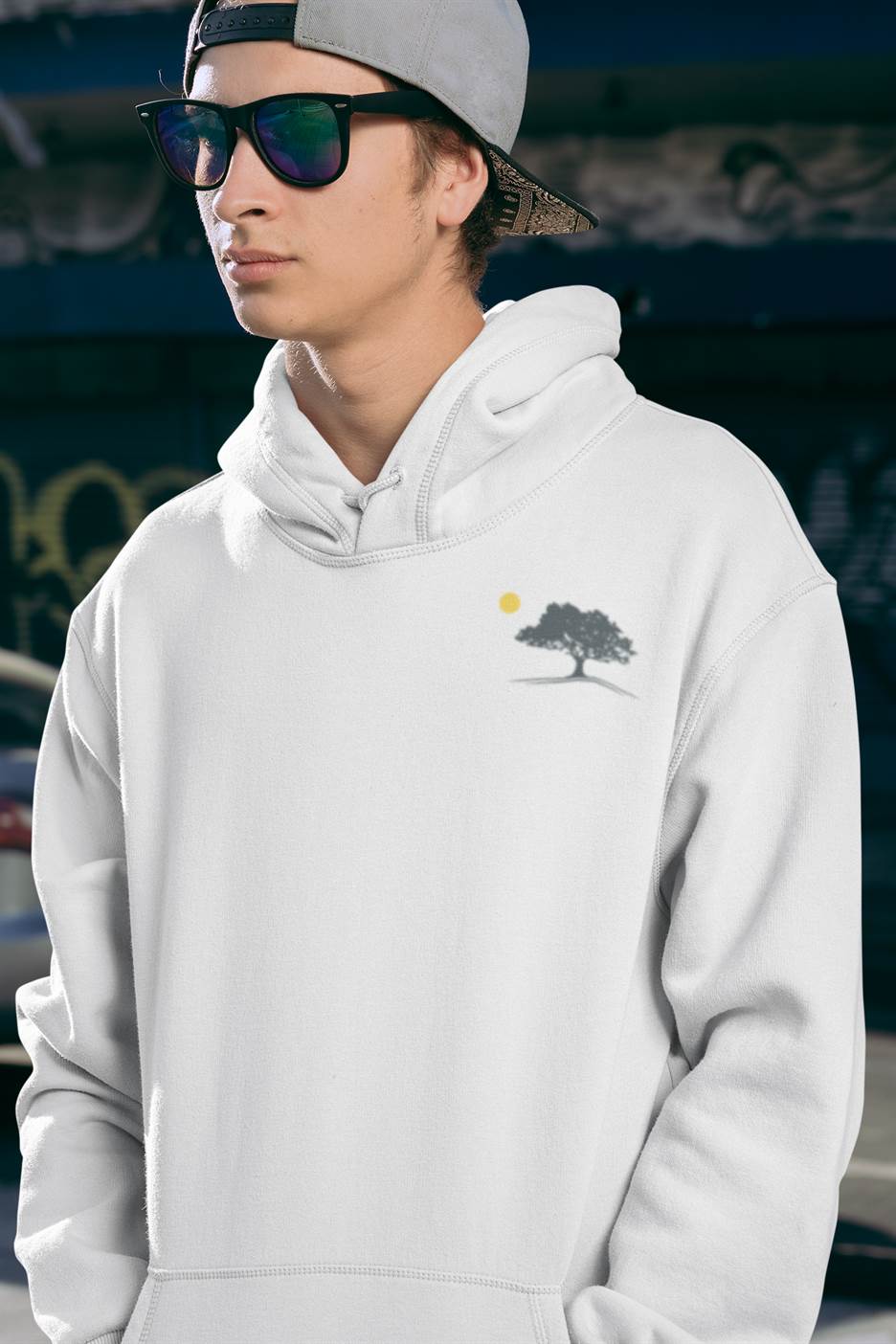 White Evora Sunset Minimal Organic Hoodie with a subtle oak tree logo, worn with sunglasses for a modern and sustainable streetwear look.