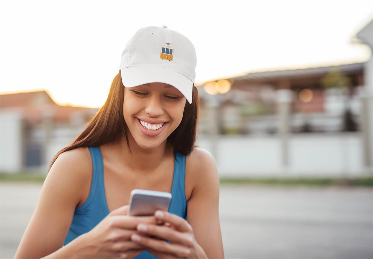 Minimalist Lisbon Tram Cap in white, worn by a smiling woman outdoors. A stylish and unisex tribute to Lisbon's historic tram culture.