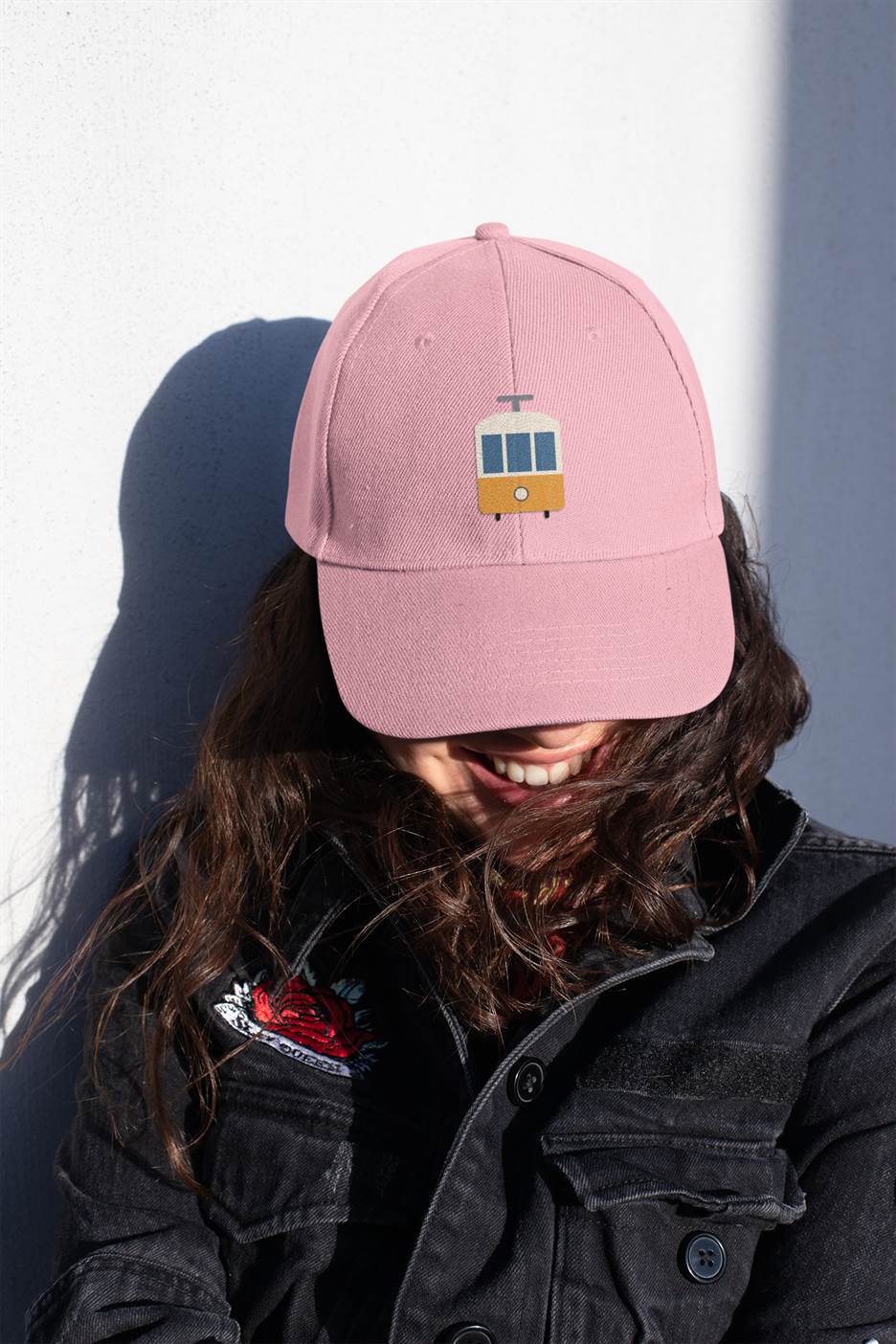 Pink Lisbon Tram Cap with minimalist embroidery, worn by a woman smiling. A fashionable unisex cap celebrating Lisbon's historic tram culture.