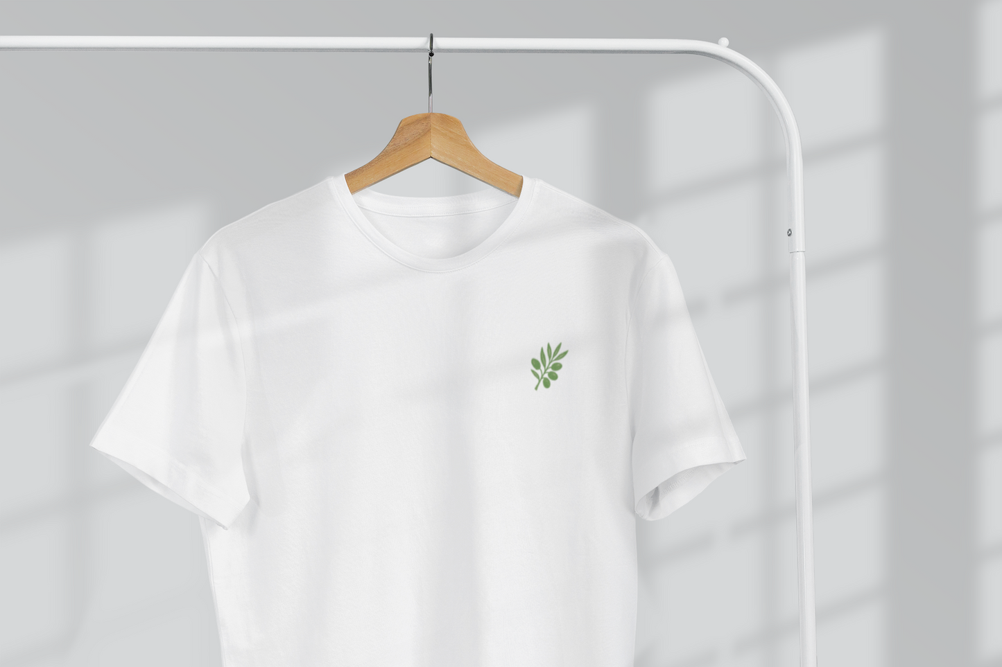 White t-shirt with a green logo on a hanger against a gray background