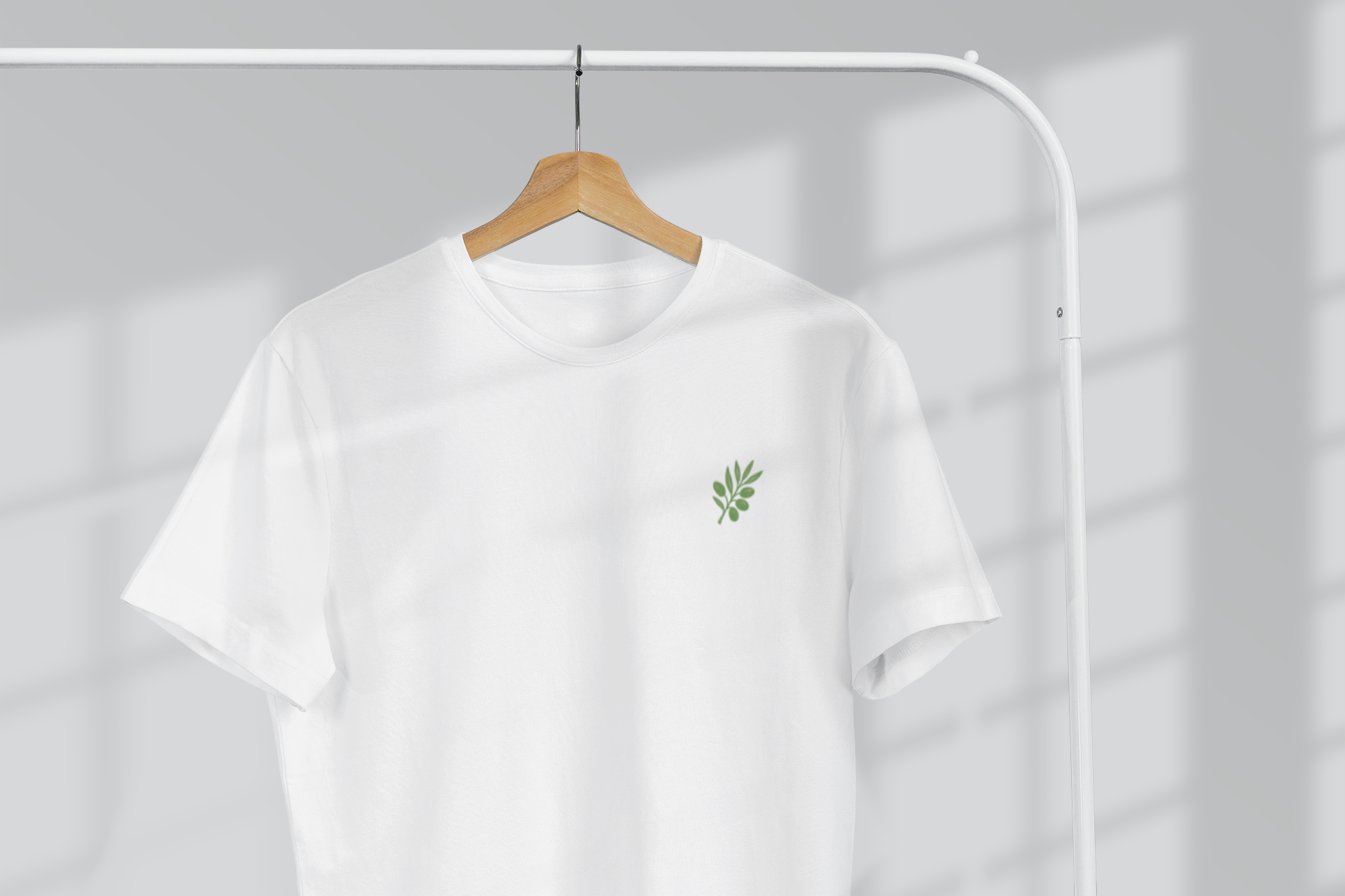 White t-shirt with a green logo on a hanger against a gray background