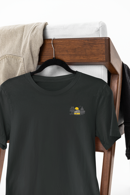 Black t-shirt with a small graphic on a wooden hanger against a white background