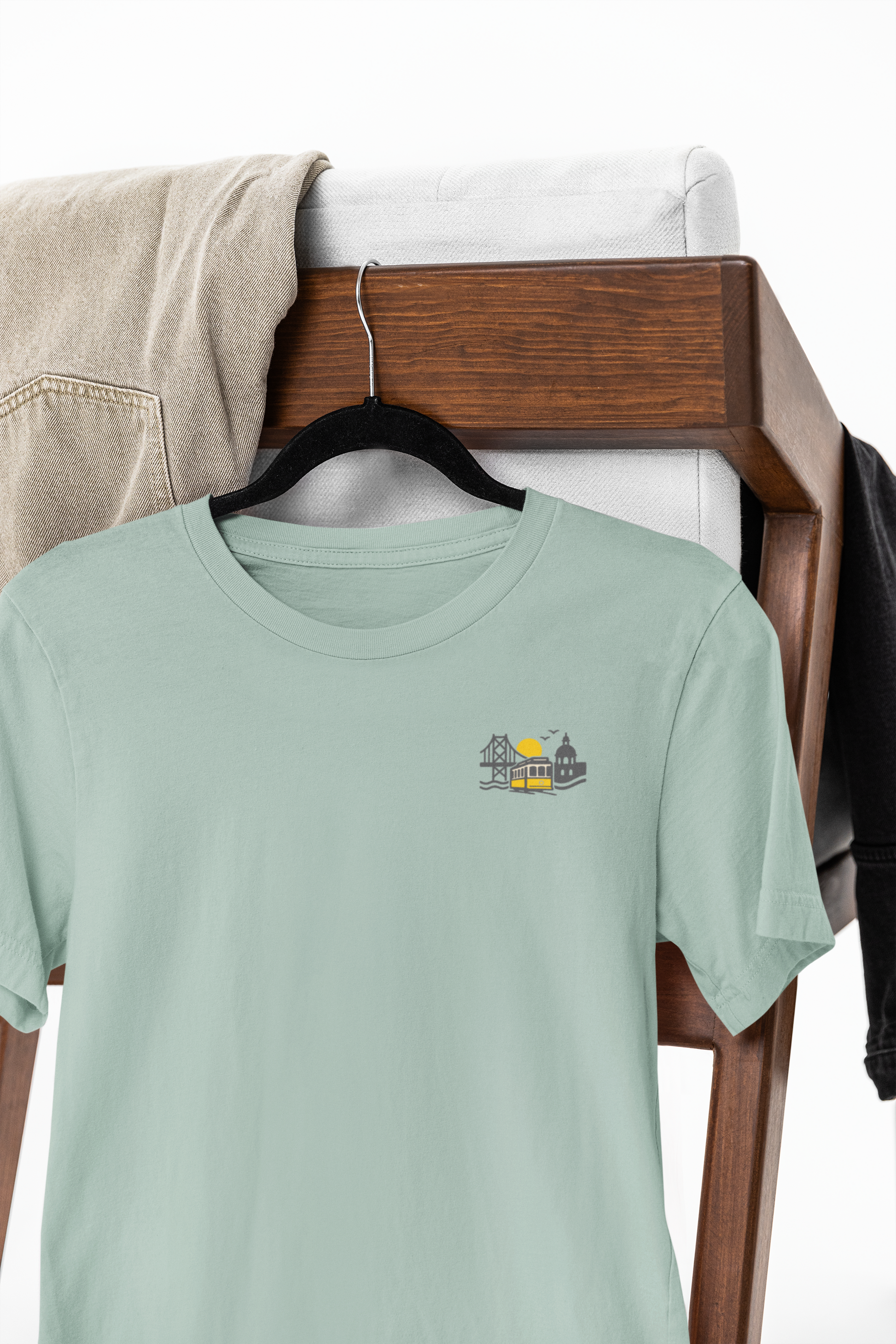 Light green t-shirt with a small graphic on a wooden rack.