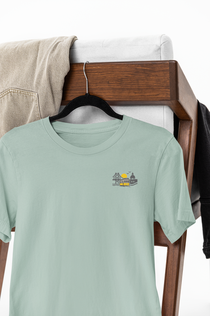 Light green t-shirt with a small graphic on a wooden rack.