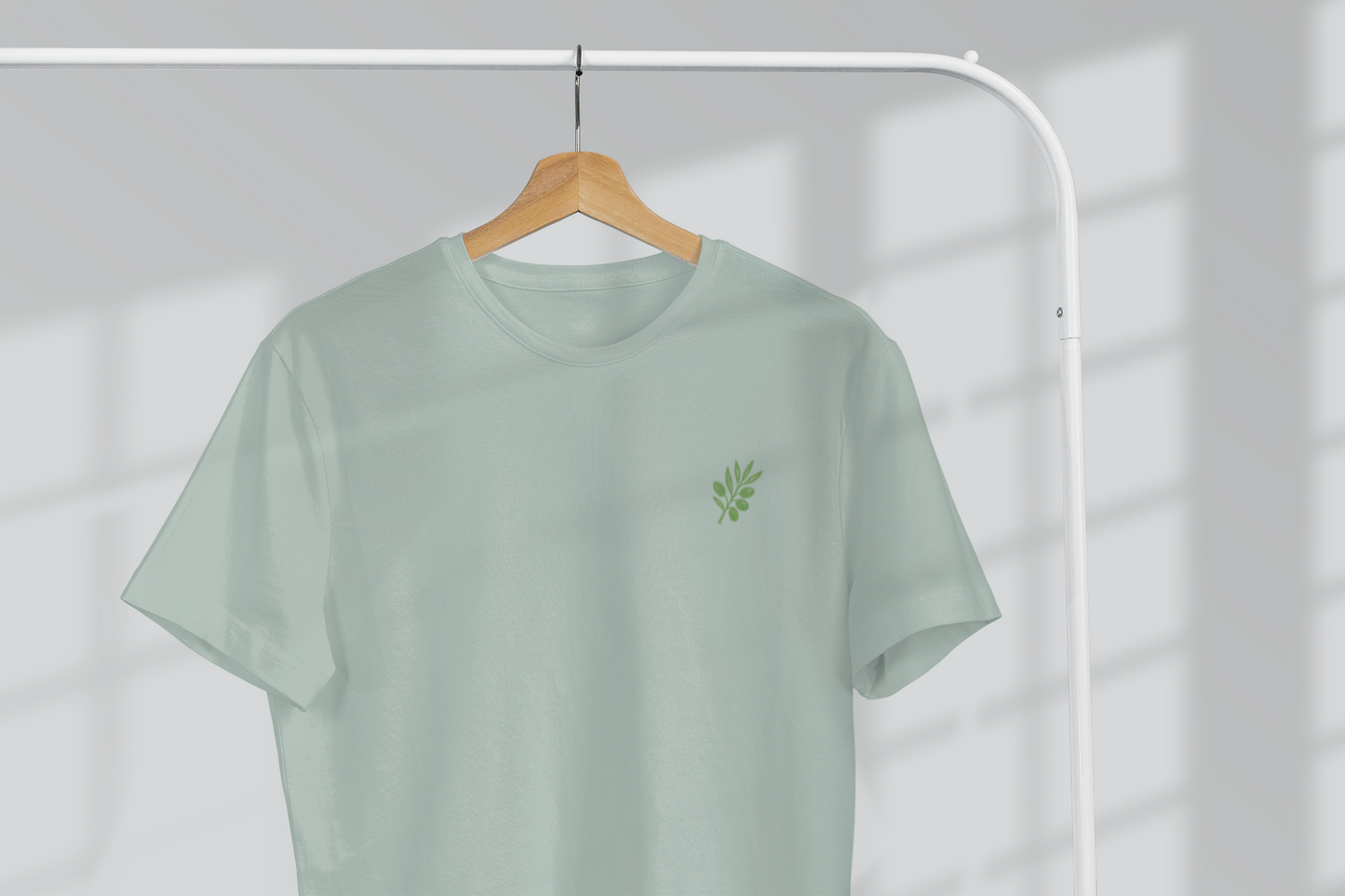 Light green t-shirt with a small logo on a hanger against a white background