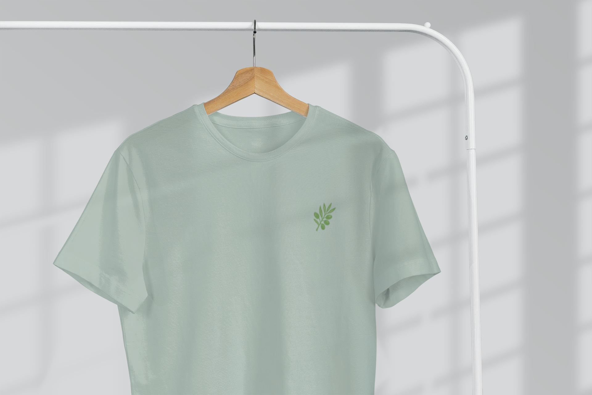 Light green t-shirt with a small logo on a hanger against a white background