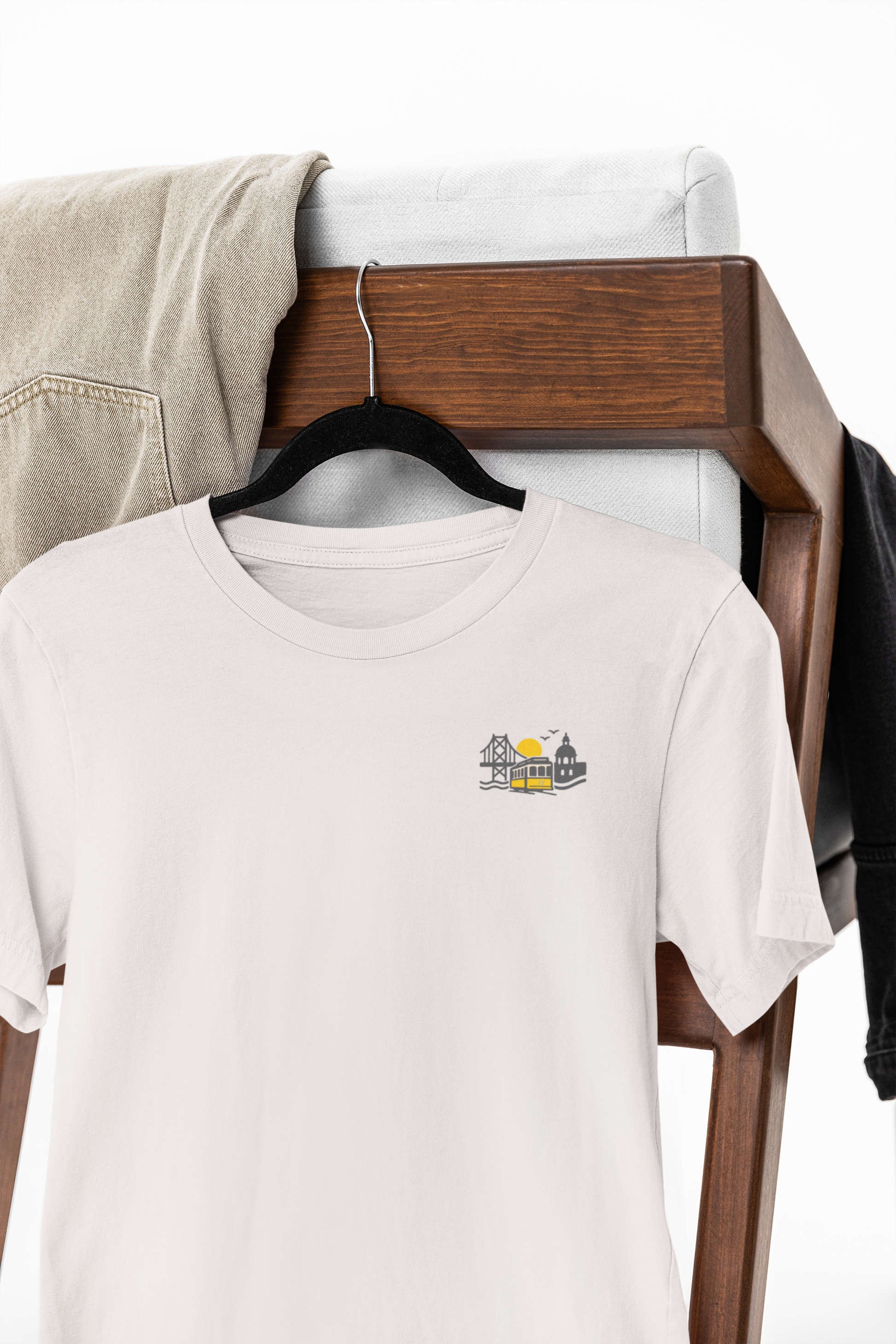 White t-shirt with a small logo on a hanger against a neutral background
