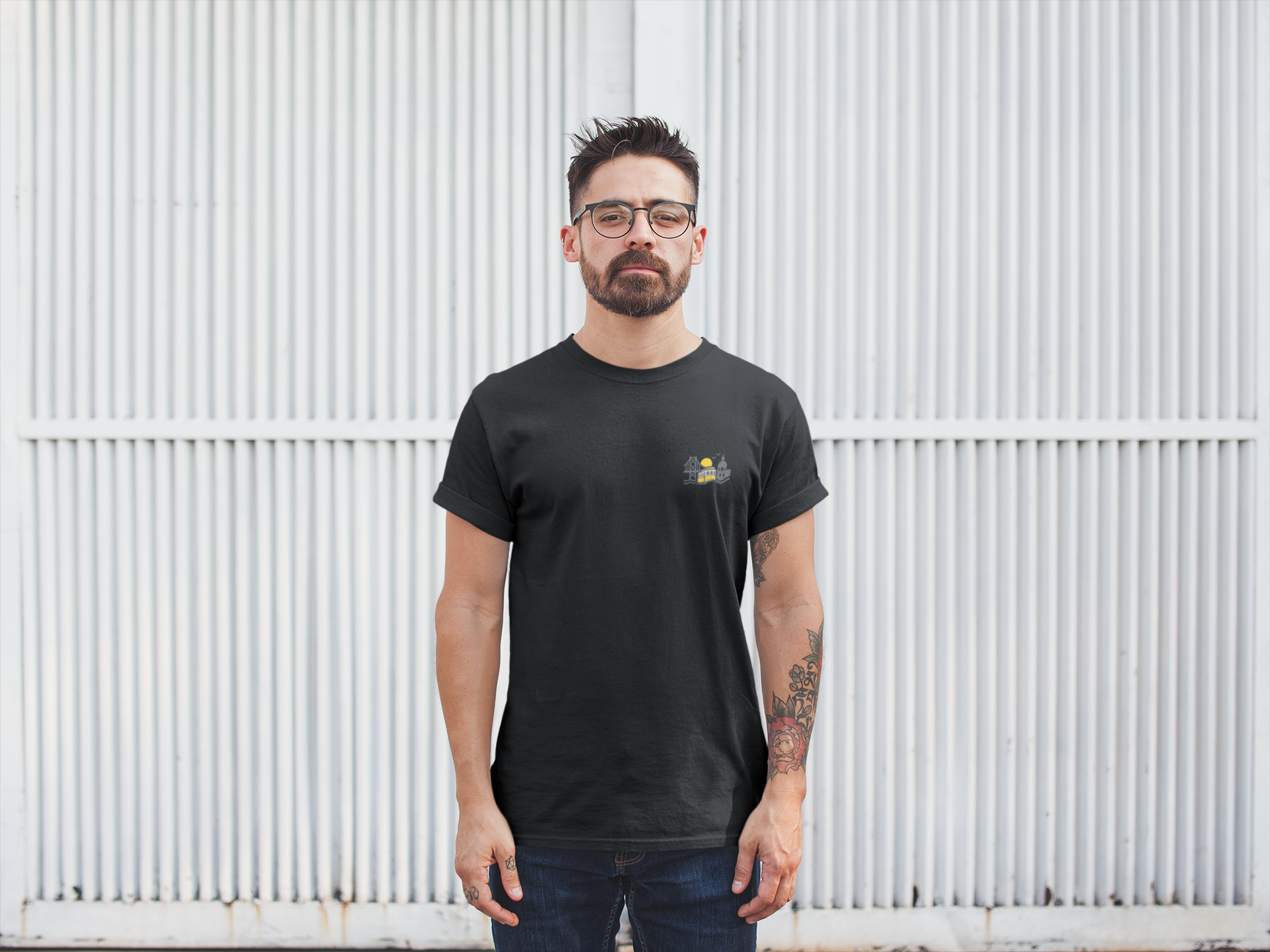 Man wearing a black t-shirt with a logo against a white corrugated metal background