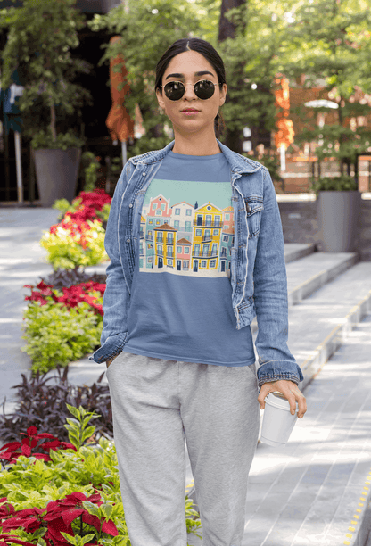 Woman in a blue unisex T-shirt with Lisbon Alfama houses print, paired with a denim jacket. Eco-friendly and comfortable for everyday wear.