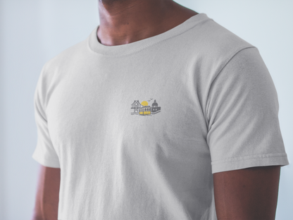 Person wearing a light gray t-shirt with a small logo on the chest against a plain background