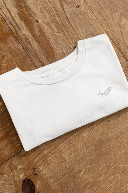 Folded white sardine t-shirt with minimalist embroidered fish design on a wooden surface. Crafted from organic cotton for an eco-friendly and stylish fit.