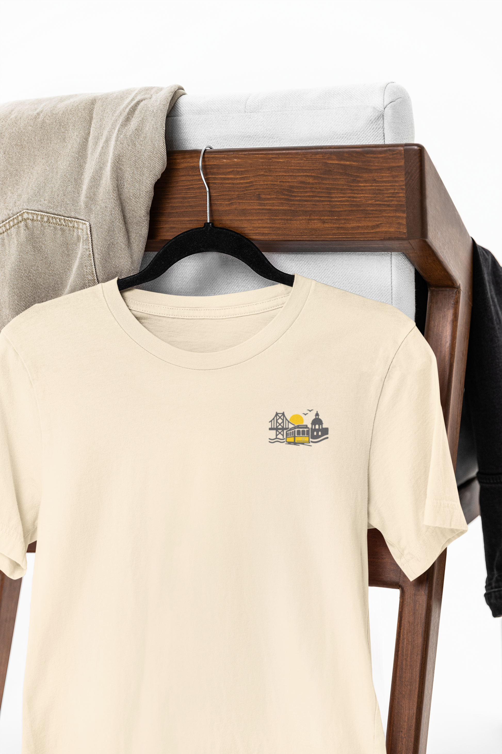 Beige t-shirt with a logo on a hanger against a wooden background