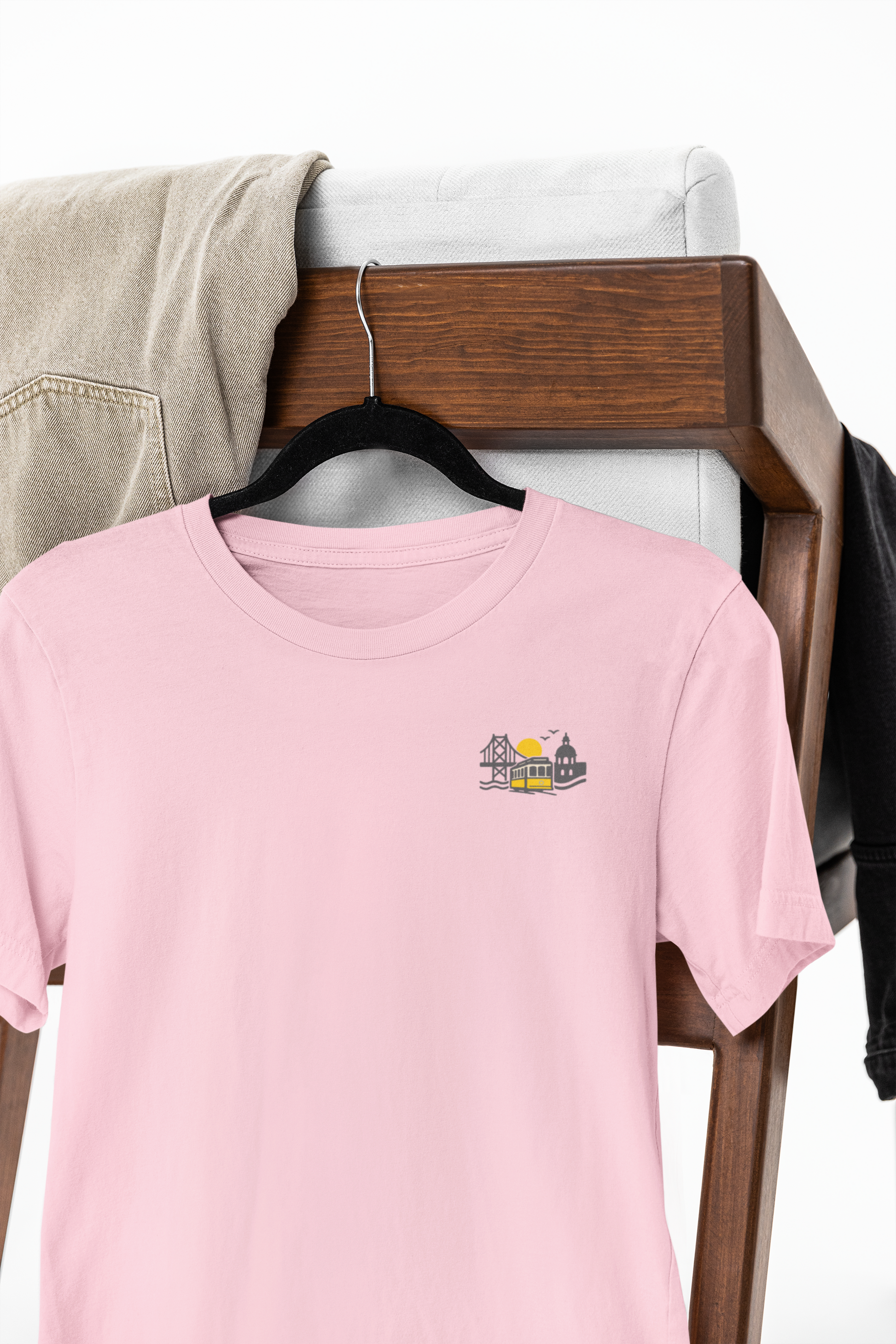 Pink t-shirt with a logo on a hanger against a wooden background