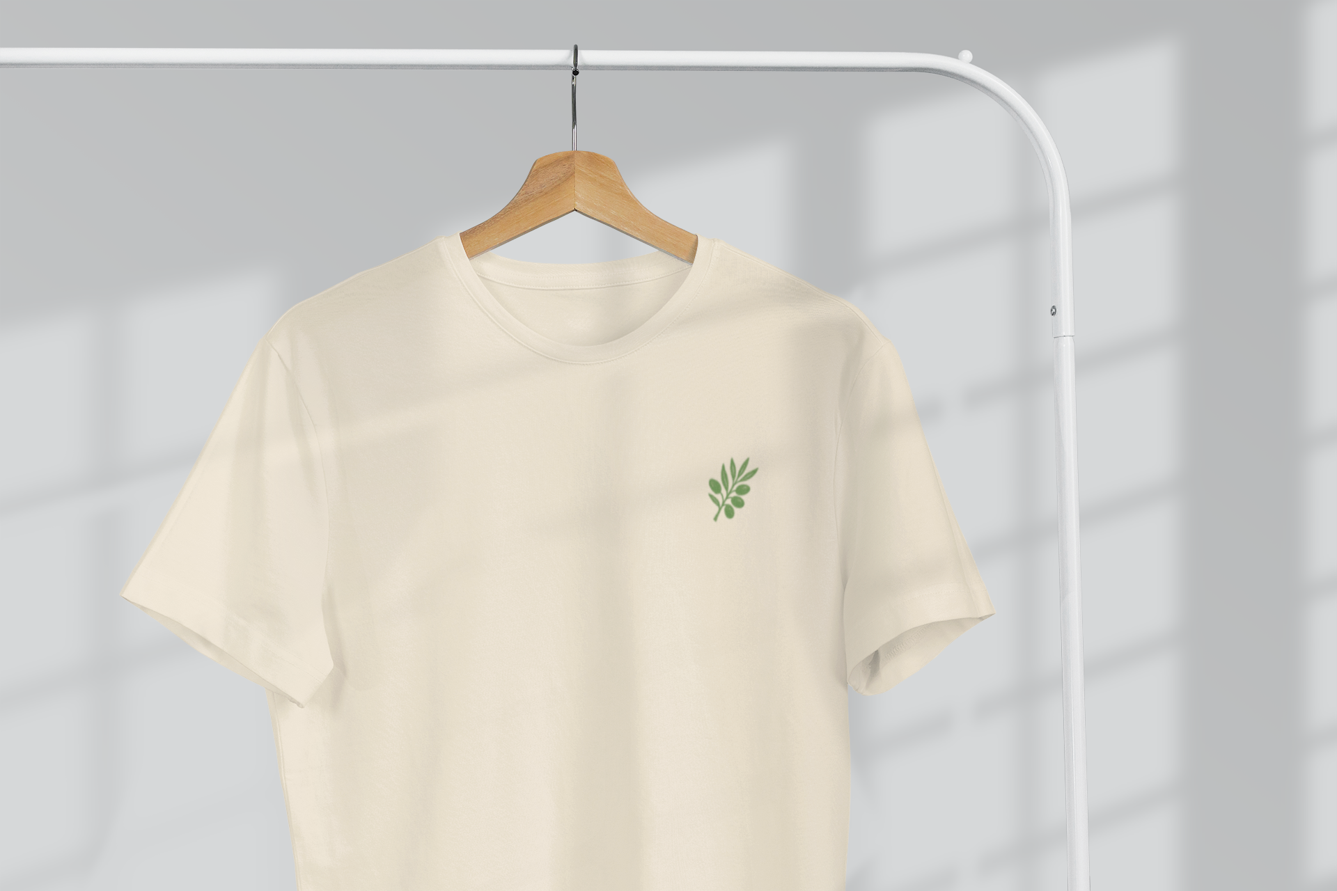 Beige t-shirt with a green logo on a hanger against a gray background